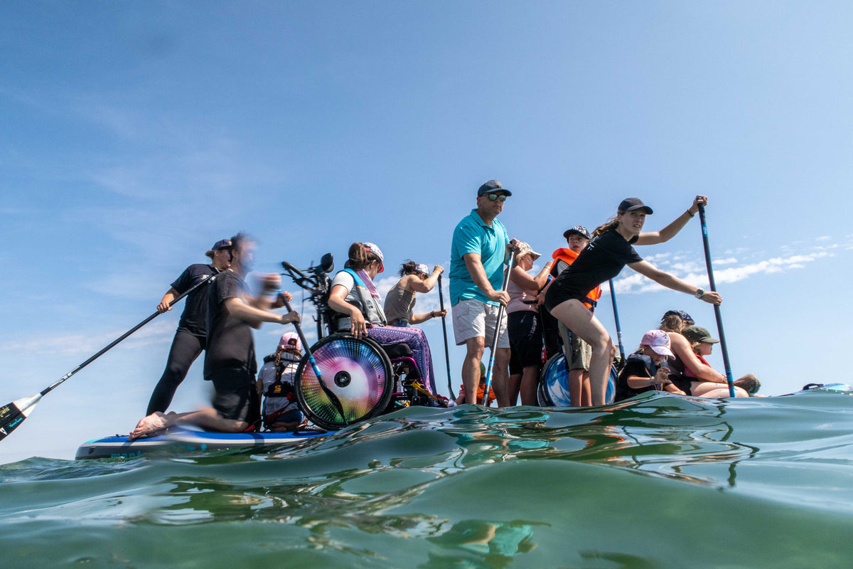 Gruppe mit Rollstuhlfahrenden beim inklusiven Stand-up-Paddling auf der Ostsee beim SUP ’N’ SKATE Event 2025 in Scharbeutz