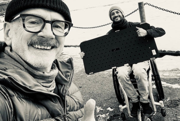 Übergabe des TRAIL-MATE-Wegesystems an Open Ocean e.V.: Selfie im Winter, dahinter ein Rollstuhlfahrer mit einer TRAIL-MATE-Wegeplatte
