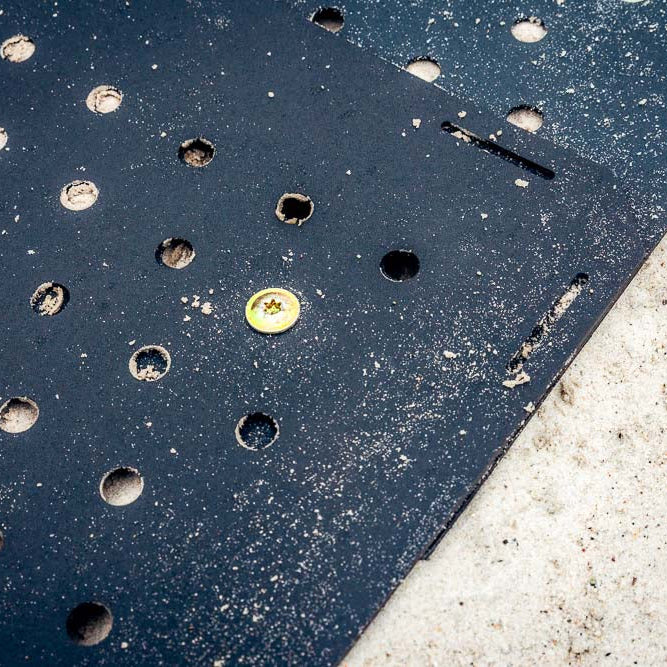 Eingeschlagener Erdnagel fixiert eine TRAIL-MATE Wegeplatte im Sand, Nahaufnahme