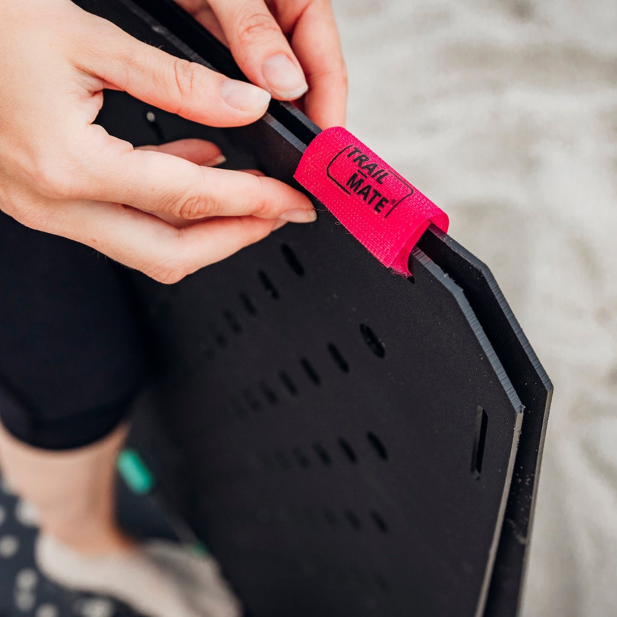 Pinker TRAIL-MATE Klettverbinder wird an einer Wegeplatte befestigt, Nahaufnahme